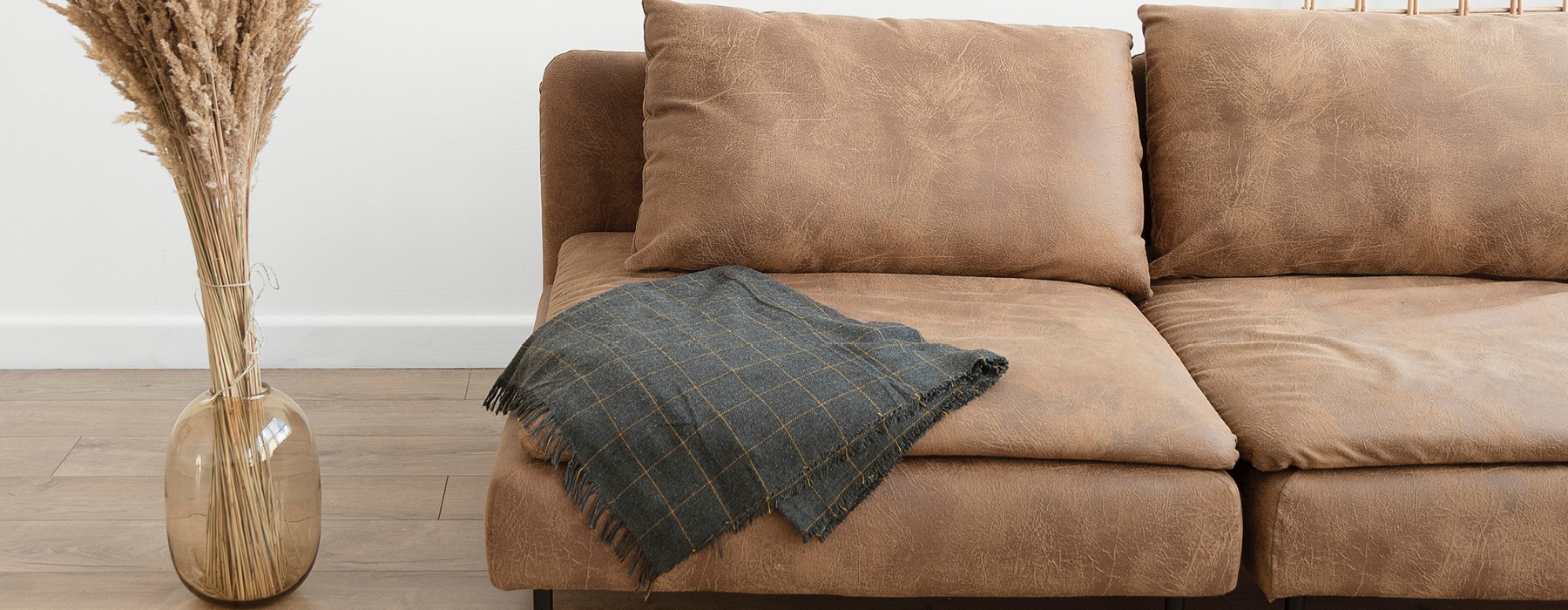 Brown sofa with a dark blanket in a spacious, well-lit room